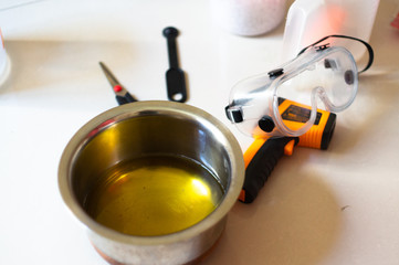 shot of steel vessel, thermometer, goggles, spatula used for making home made hand made soap with blurred background