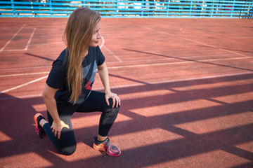 Athletic girl kneeling, trying to get up