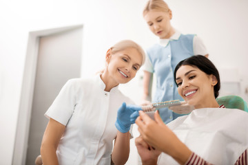 Obraz na płótnie Canvas Dentist helping her patient choosing teeth whitening samples.