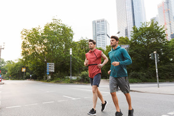 Photo of two athletic young men doing workout and running on city street