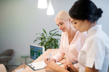 Woman signing a contract with her dentist.