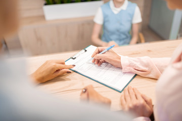 Doctor pointing her patient where to sign the form.