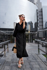 Woman in black kimono talking on the phone on the background of a modern building