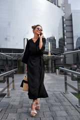 Obraz premium Woman in black kimono talking on the phone on the background of a modern building