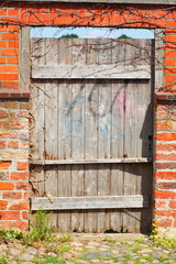 Alte braune Holztür an winer alten Ziegelmauer,  Lübeck, Schleswig-Holstein