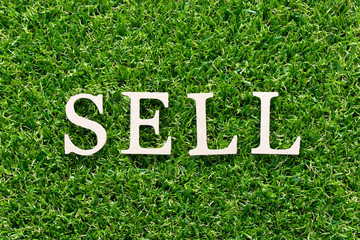 Wood alphabet in word sell on artificial green grass background