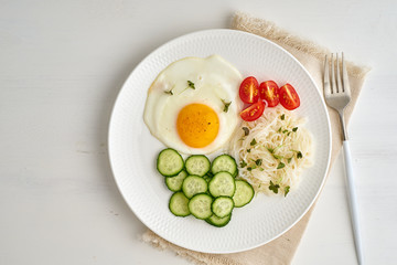 Healthy breakfast - fried egg with cherry tomatoes and cucumber on light white background, fodmap dash diet, gluten free, top view closeup copy space