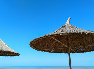 Straw umbrellas against a blue sky. Parasols.