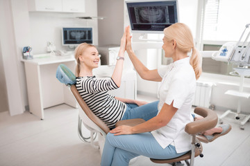 Dentist giving her happy patient a high-five.