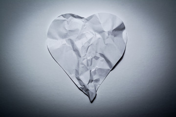 Heart symbol made from old, crumpled paper on a white vintage background. Symbol of a broken heart, unhappy love.