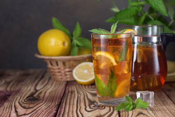 Glass of iced tea with mint and lemon. Cold drink. Rustic style