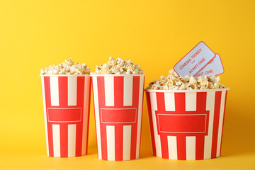 Striped buckets with popcorn on yellow background, copy space