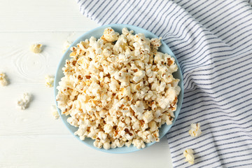 Flat lay composition. Towel and plate with popcorn on white wood background