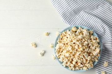 Flat lay composition. Towel and plate with popcorn on white wood background