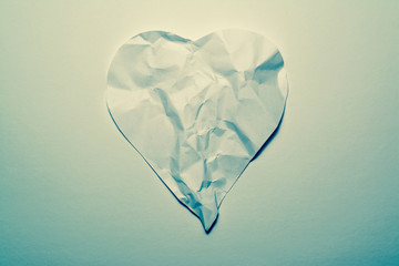 Heart symbol made from old, crumpled paper on a white vintage background. Symbol of a broken heart, unhappy love.