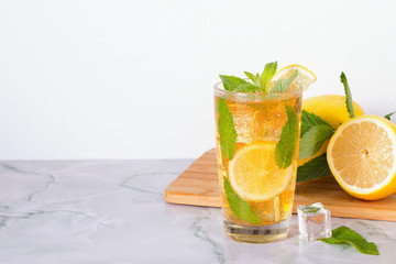 Glass of iced tea with mint and lemon on marble table. Cold drink.