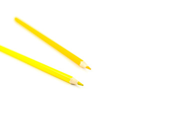 Two yellow pencils on a white background. Selective focus on nearest pencil