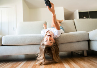 A girl holding remote control and watching TV show