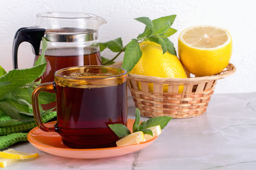 Glass of tea with mint and lemon on marble table.