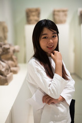 Thoughtful chinese woman in historical museum looking at art object