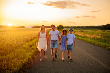 Naklejka na ściany i meble happy family at sunset. They having fun and playing in nature at sunset