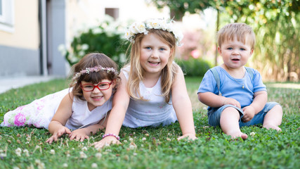 drei Kinder in der Wiese spielen, Geschwister im Garten, Party