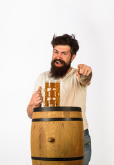 Oktoberfest. Bearded man with glass of beer points forward. We meet oktoberfest. Germany traditions. Man holding mug of beer. Concept of craft beer. Wooden barrel and glass of beer.