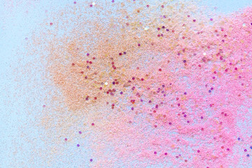 Many multi-colored spangles are scattered on a blue background.  View from above.  Place for text.