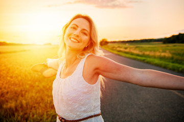 Woman on a hay field at the sunset with hat