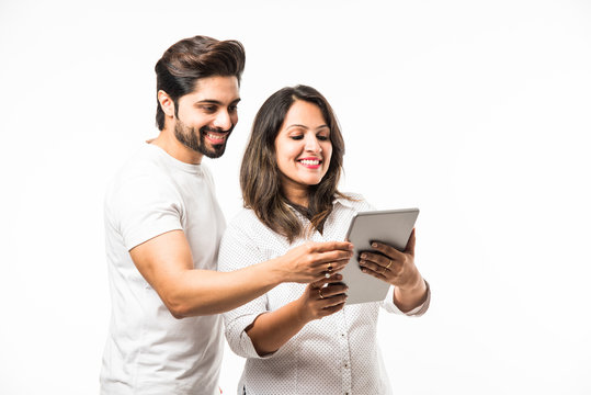 Indian couple using tablet computer while standing isolated over white background