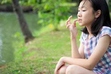 Asian little child girl feeling stressed,female worried bites finger nails in park,girl patient with nervous expression,nail biting,anxious with hand on mouth biting her nails,anxiety problem,