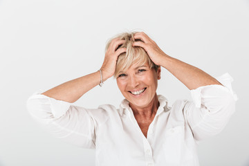 Portrait of delighted adult woman with short blond hair grabbing her head and laughing at camera