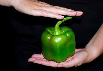 Juicy ripe bell peppers in female hands on a black background, home cooking