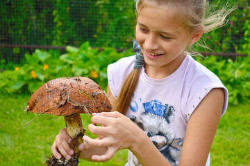 Beautiful cheerful girl with a big mushroom in hands.