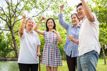 Hooray,Yeah,happy asian family raised fists up with triumph,yelling excited,achievement,successful deal,joyful,delight impressed about their luck in lottery,father,mother,daughter,grandmother in park
