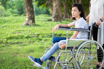 Disabled daughter in wheelchair feeling sad,asian little child girl with depressive symptoms,left...