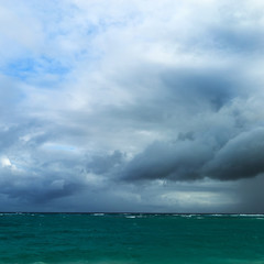 The beginning of a storm on a wild ocean beach in a sandy bay of a blue tropical sea
