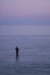 Fototapeta na wymiar Red violet sunset sky, calm see and a fisherman, France