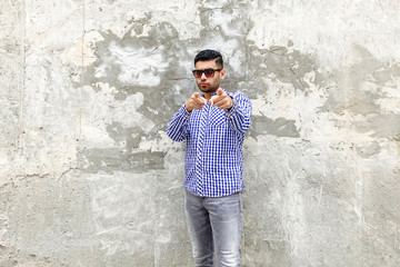 Hey you. Portrait of serious handsome bearded young man in checkered blue shirt and sunglasses...
