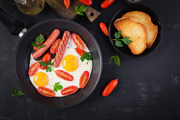 English breakfast - fried egg,  tomatoes, sausage,  and toasts. Top view, overhead