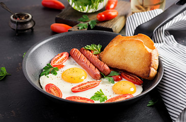 English breakfast - fried egg,  tomatoes, sausage,  and toasts. Top view