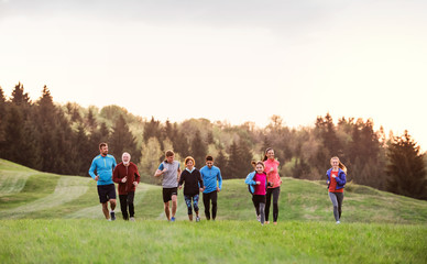 A large group of people cross country running in nature.