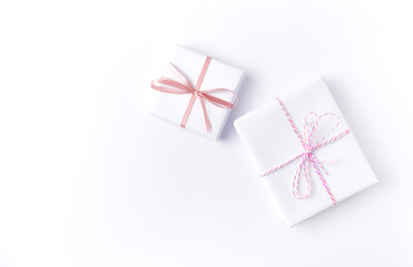White gift boxes with pink ribbon on white background. Flat lay. Copy space