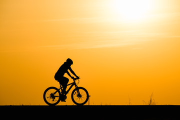 Obraz premium Silhouette woman cycling on sunset background