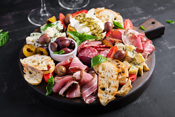 Antipasto platter with ham, prosciutto, salami, blue cheese, mozzarella with pesto and olives on a...