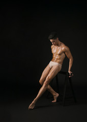 Muscular dancer leaning on barre