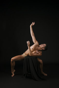 Man standing on toes crouching leaning on chair