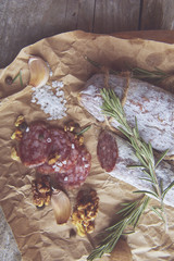 French salami and walnuts on craft paper on wooden background