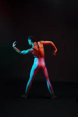 Unrecognizable ballet dancer in leotard with bent arms in spotlight
