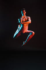 Handsome male ballet dancer performing in spotlight